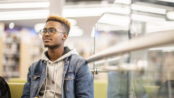 Personne assise dans une bibliothèque avec un livre à la main.